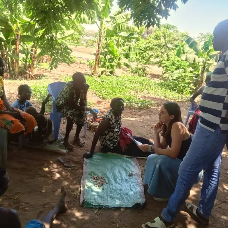 Trainees with community members in the shade during field practice in Natoot.