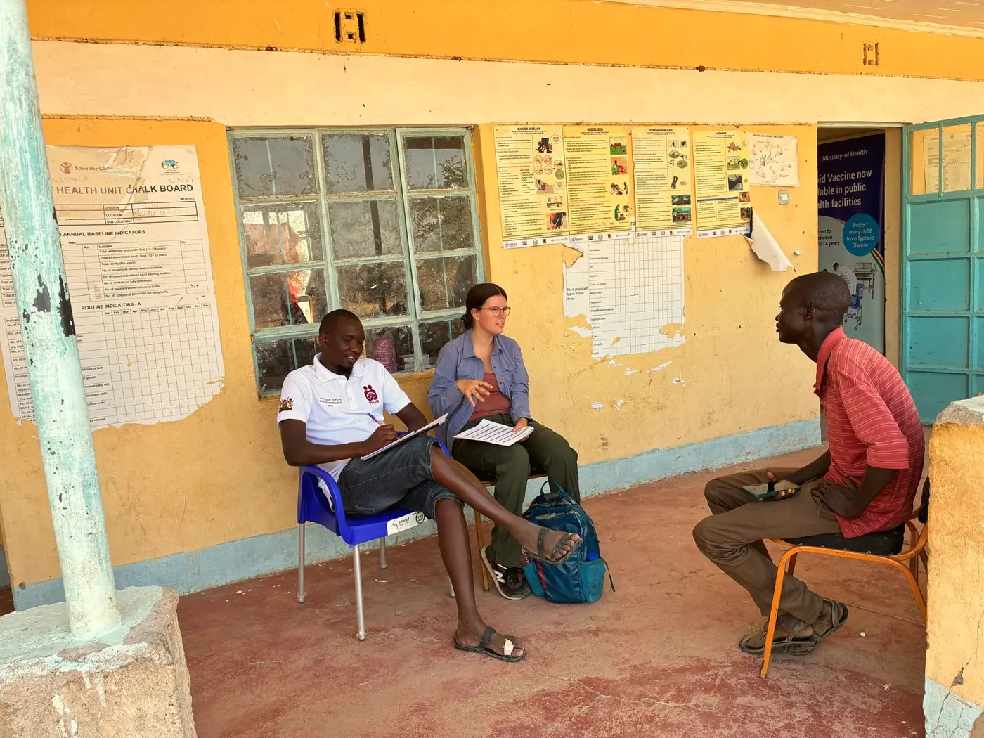 Erupe Godwin and Clara Goltz conduct a key informant interview on the veranda of a health facility.