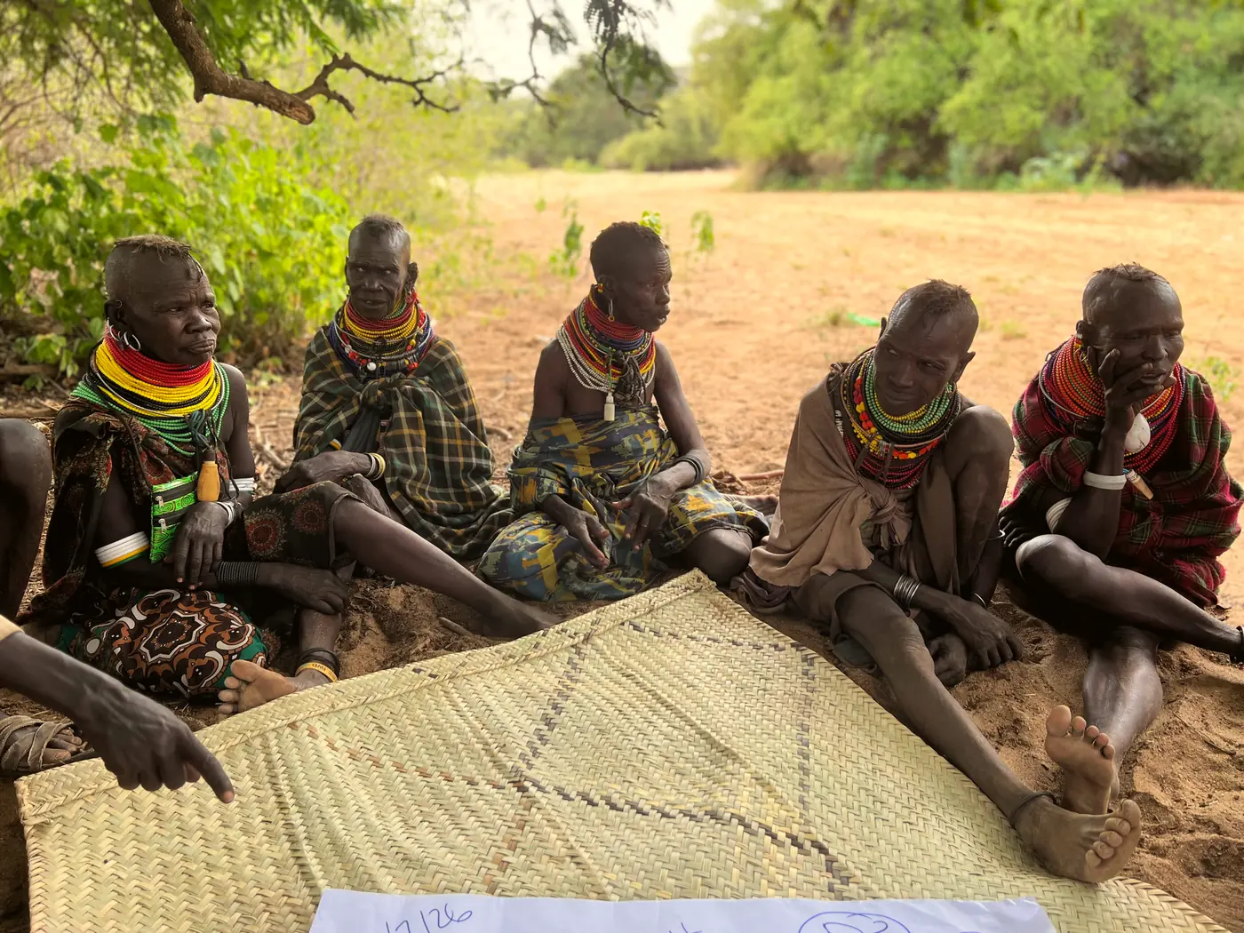 Women seated in a row on a woven mat during a COHI focus group discussion in Komio.